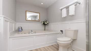 A bathroom with a white bathtub, a toilet, a sink, and a mirror.