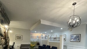 Amplia sala de estar con chimenea de piedra, un candelabro y una escalera que lleva a un nivel superior.