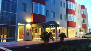 Een hotel met meerdere verdiepingen, een moderne gevel, grote ramen en een goed verlichte entree.