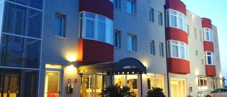 A multi-story hotel with a modern facade, large windows, and a well-lit entrance.
