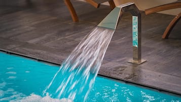 A modern showerhead with water flowing into a pool.