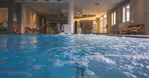 An indoor swimming pool with clear water, a lifebuoy, and lounge chairs. - Formula International & Puravita SPA (Rosolina)