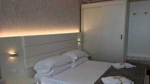 Hotelkamer met een bed, nachtkastje, kledingkast en bureau met een handdoek.