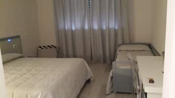 Une chambre d’hôtel avec deux lits, un bureau et une chaise.