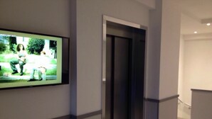 Un pasillo con un televisor en la pared que muestra una escena de personas al aire libre.