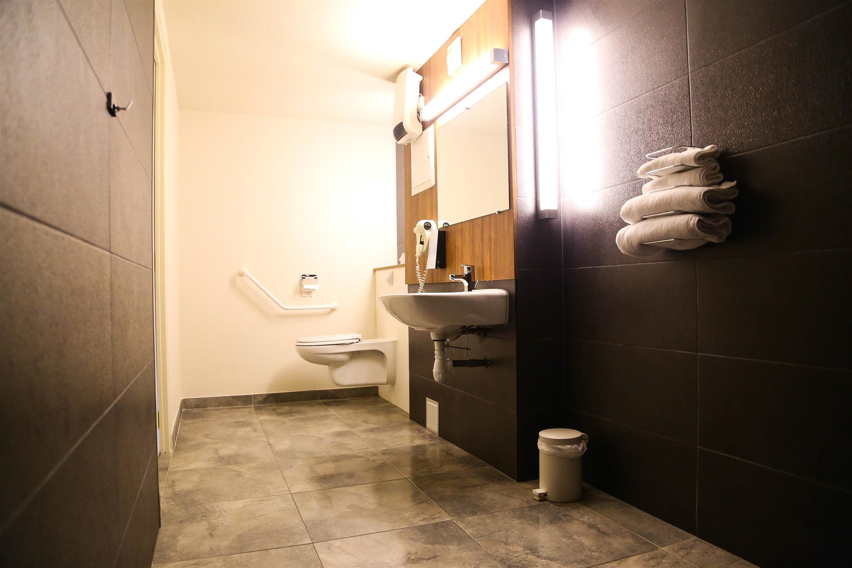 A small bathroom with a sink, mirror, towel rack, and toilet.