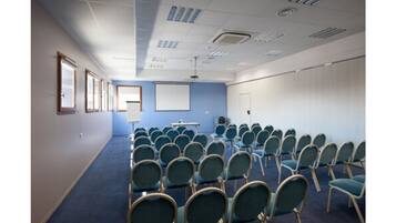 A conference room with rows of chairs, a projector screen, and a whiteboard.