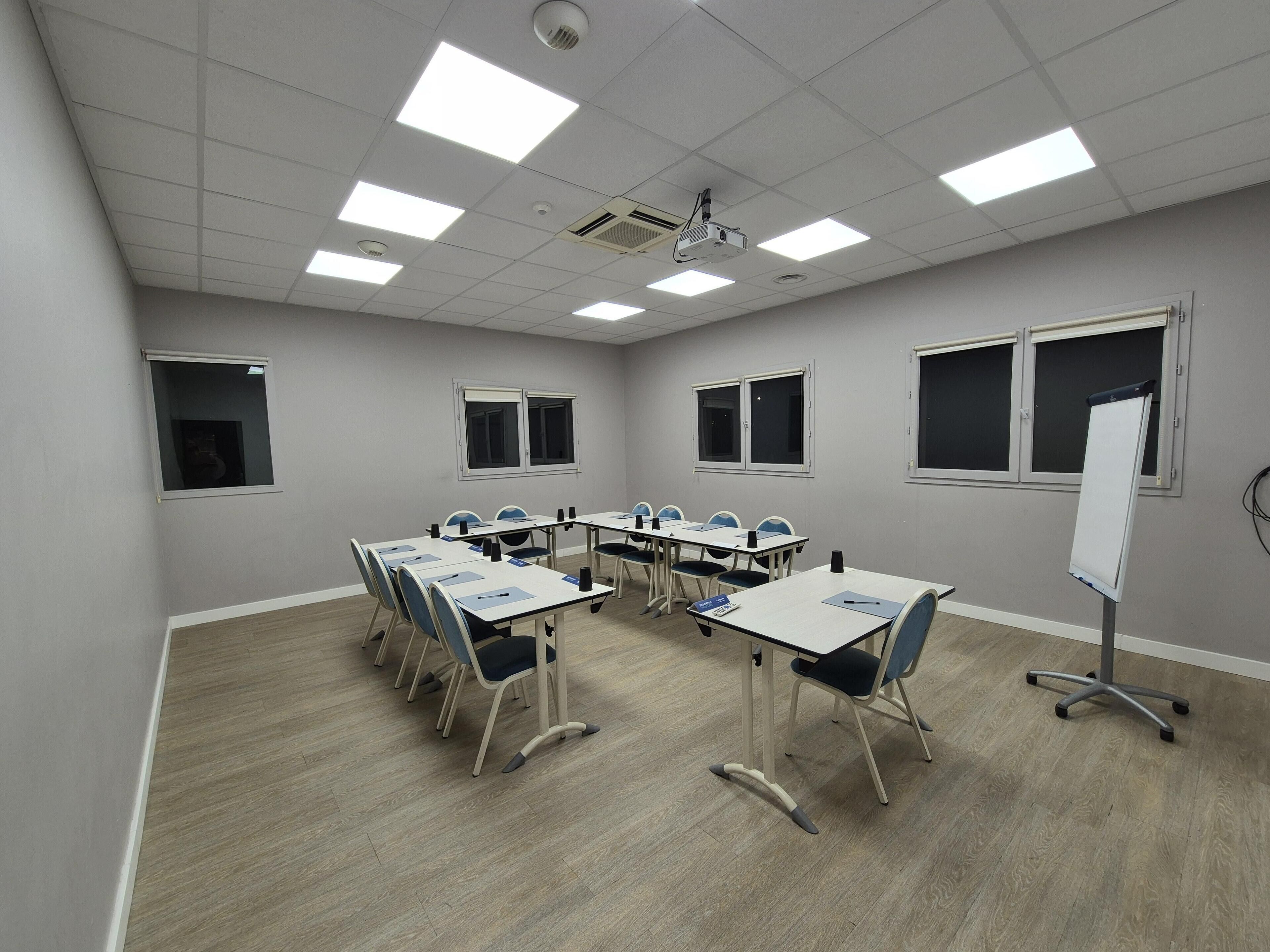 A conference room with a whiteboard, multiple tables, and chairs.