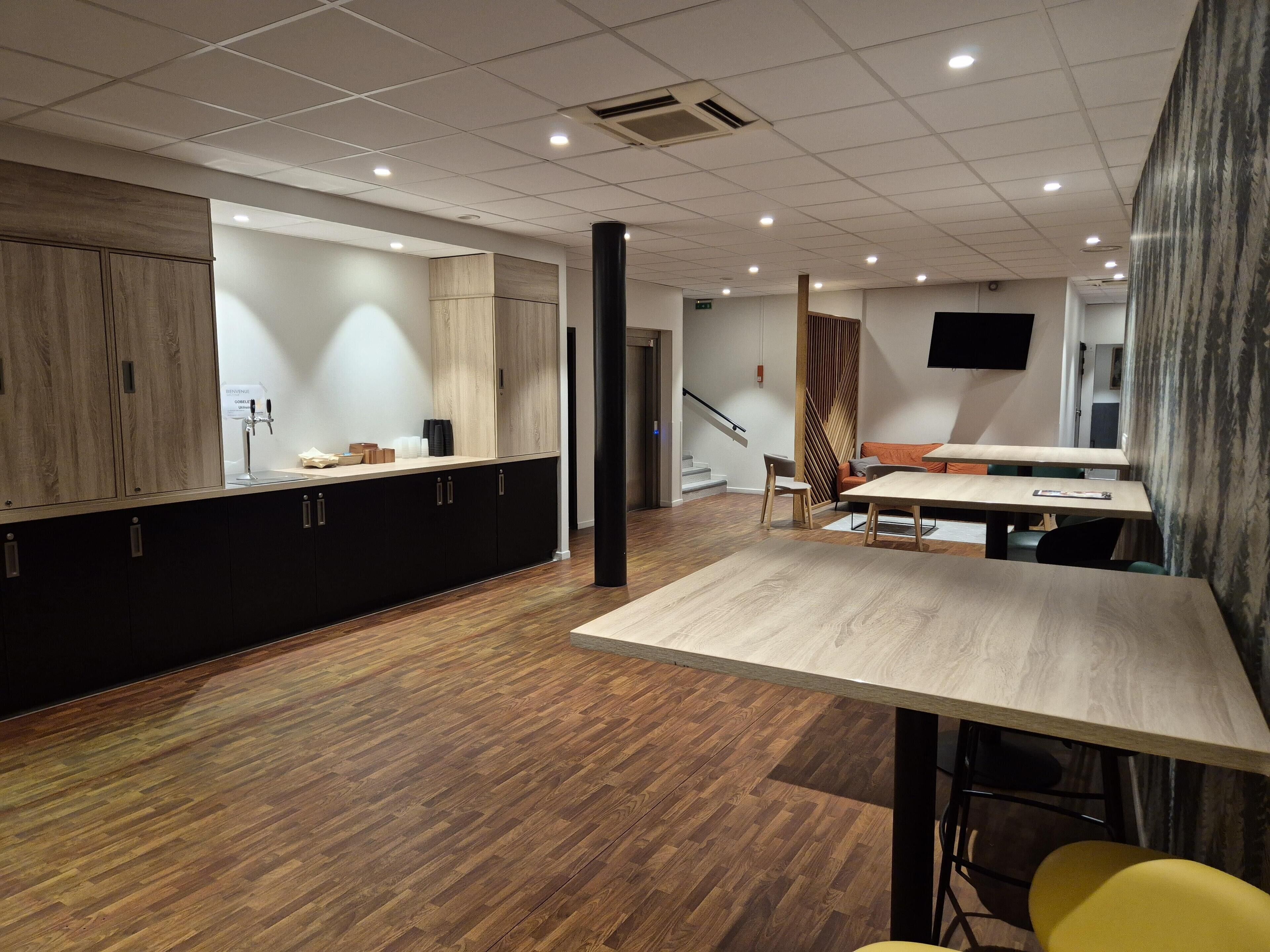 Un interior moderno con área de cocina, suelo de madera y comedor con mesa y sillas.
