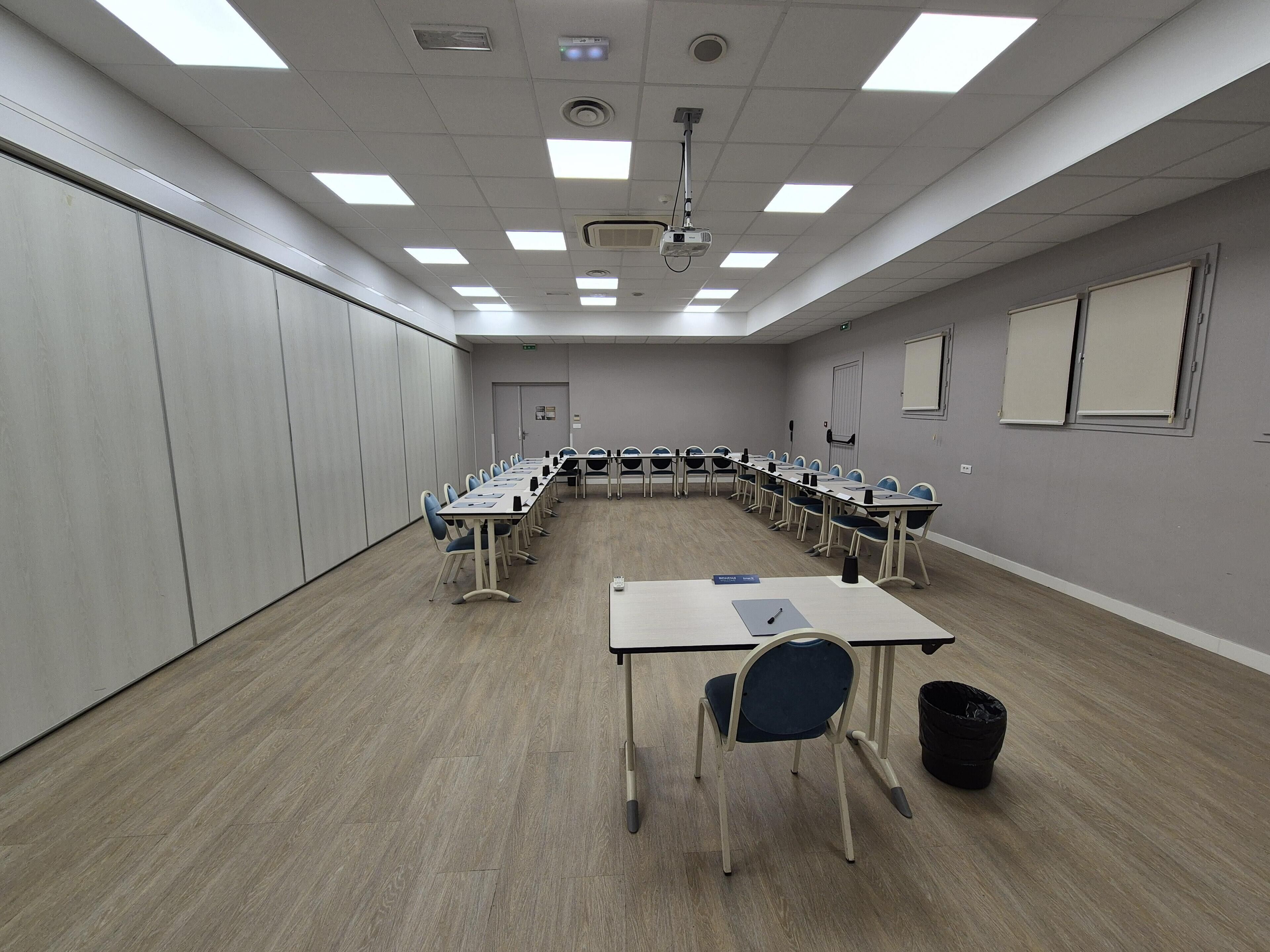 A conference room with a long table, chairs, a projector, and a whiteboard.