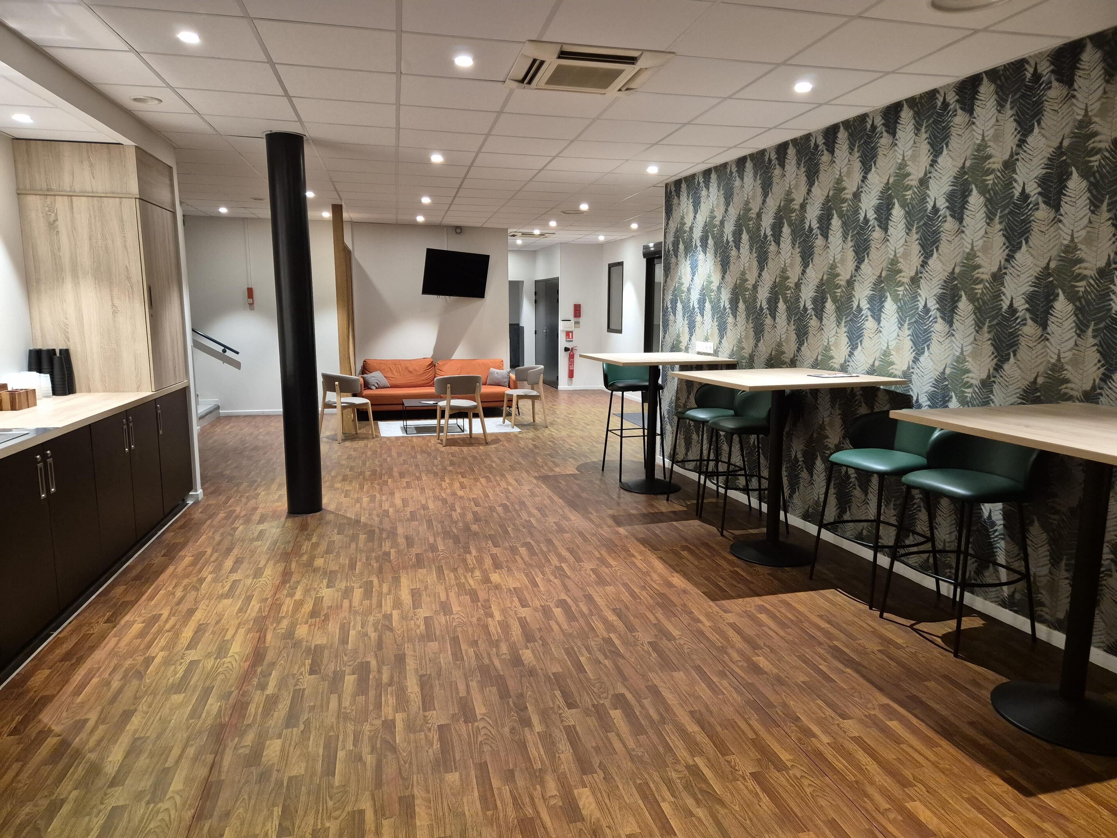 A modern interior with a wooden floor, a sofa, a TV, and a patterned wall.