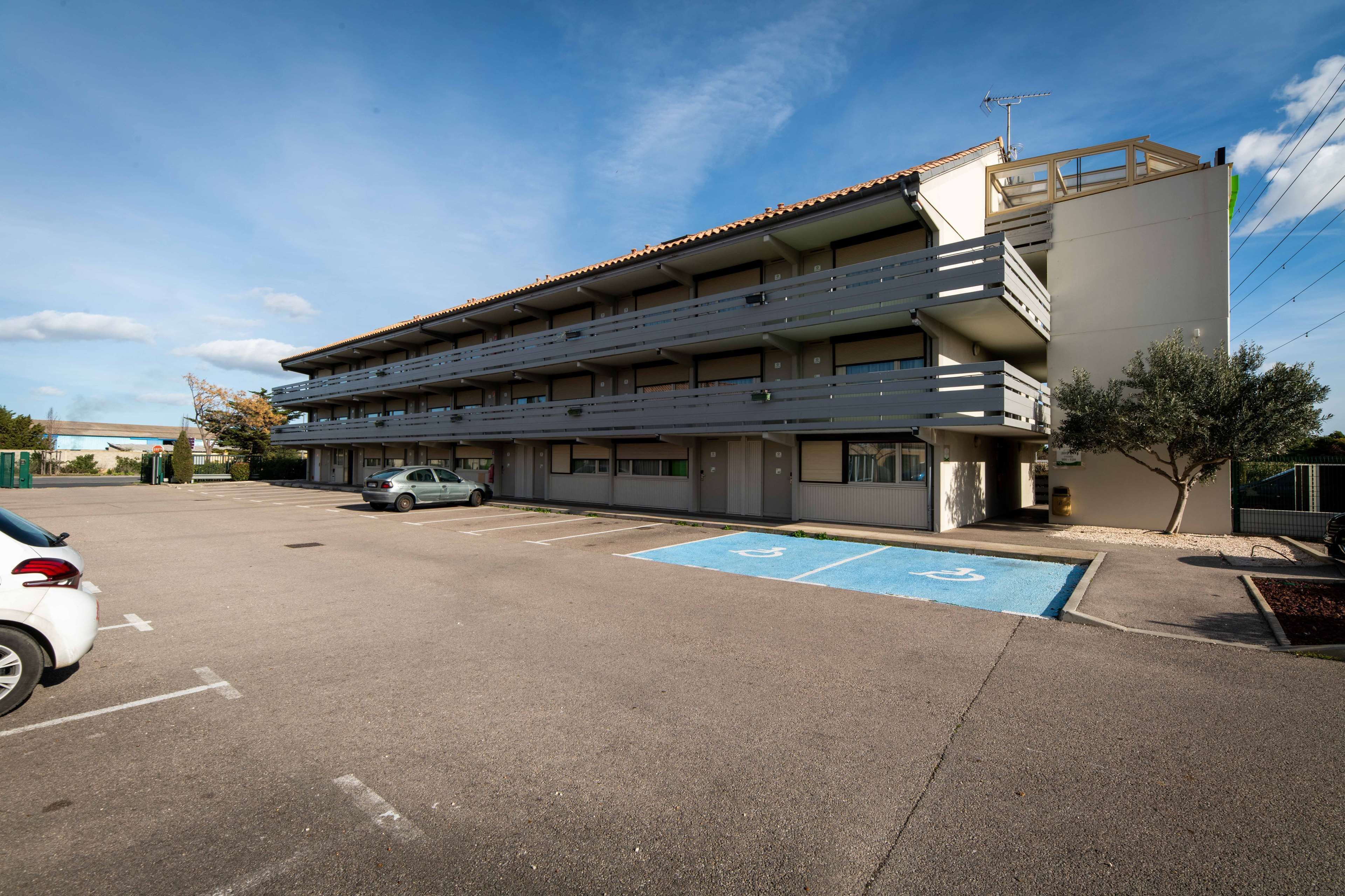 A multi-story building with a parking lot and a blue handicapped parking space.
