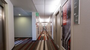 Ein Hotelkorridor mit Teppichmuster, Pfeilbeschilderung und einem Servicehinweis.