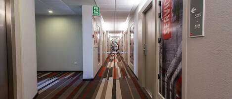 A hotel corridor with a patterned carpet, directional signs, and a service sign.