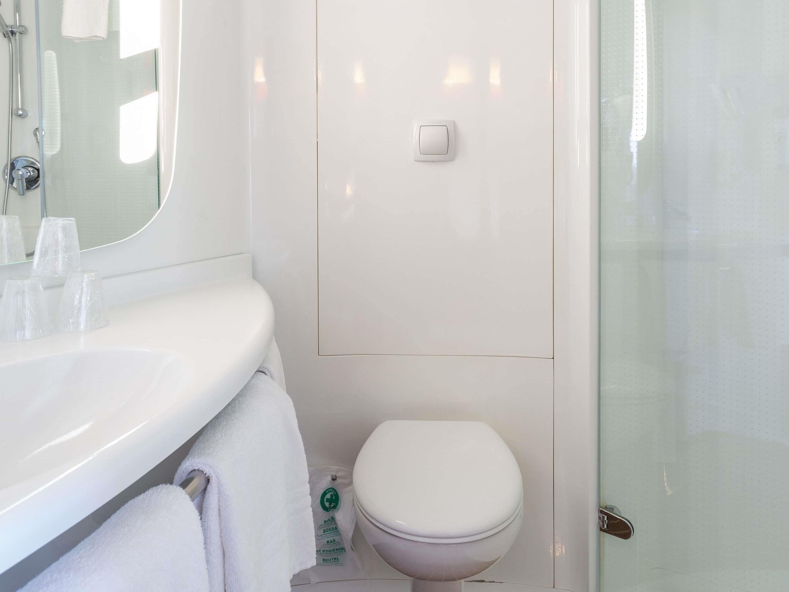 A bathroom with a white sink, a toilet, and a glass shower enclosure.