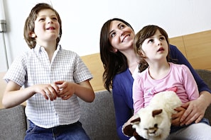 Three people sitting on a couch, one holding a stuffed animal. - Hotel ibis Elche (Elche)
