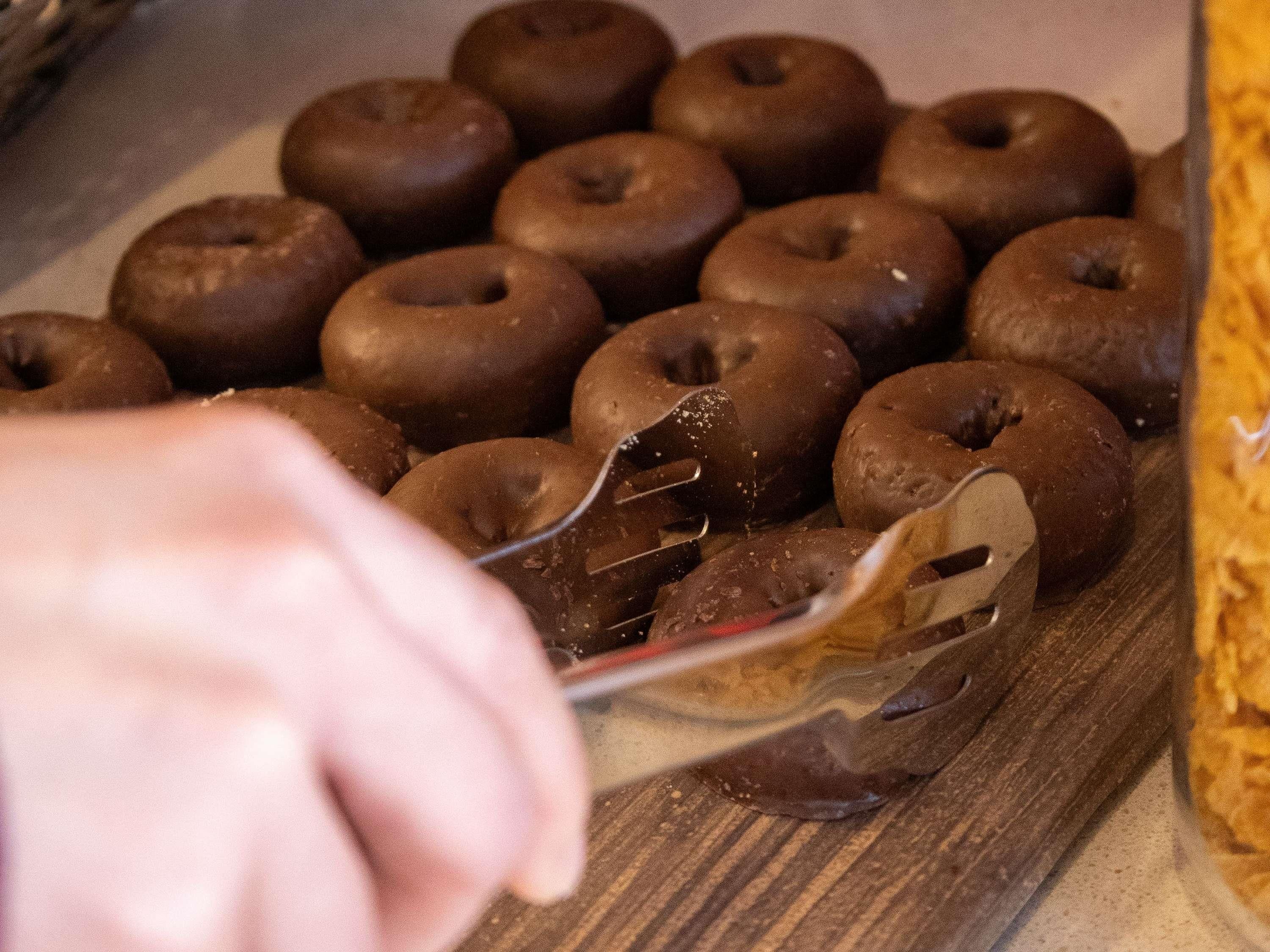 Een schaal met chocoladedoughnuts op een houten ondergrond.