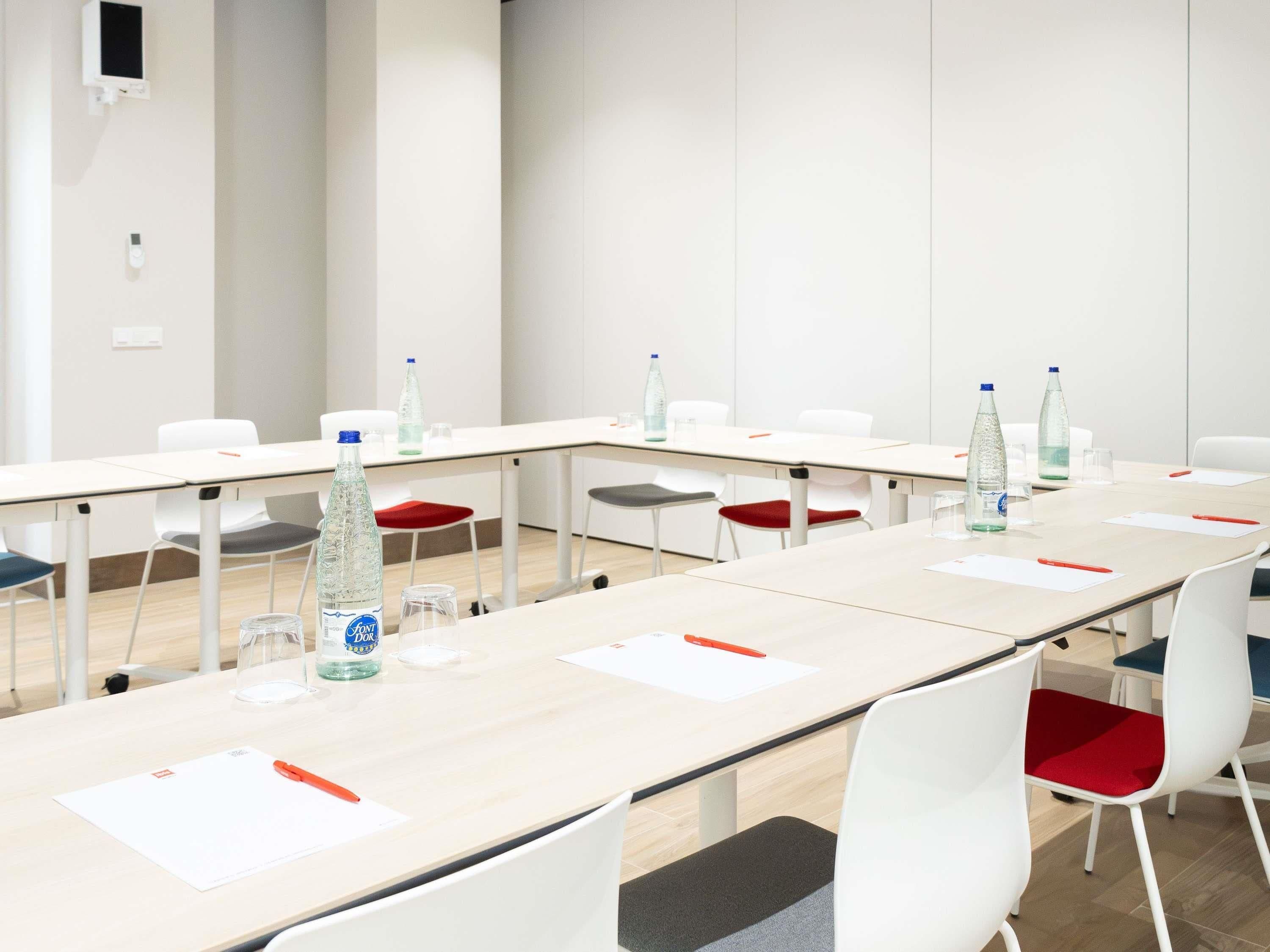 A conference room with long tables, white chairs, and water bottles.
