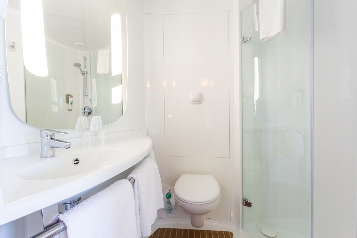A modern bathroom with a white sink, mirror, and glass shower enclosure.