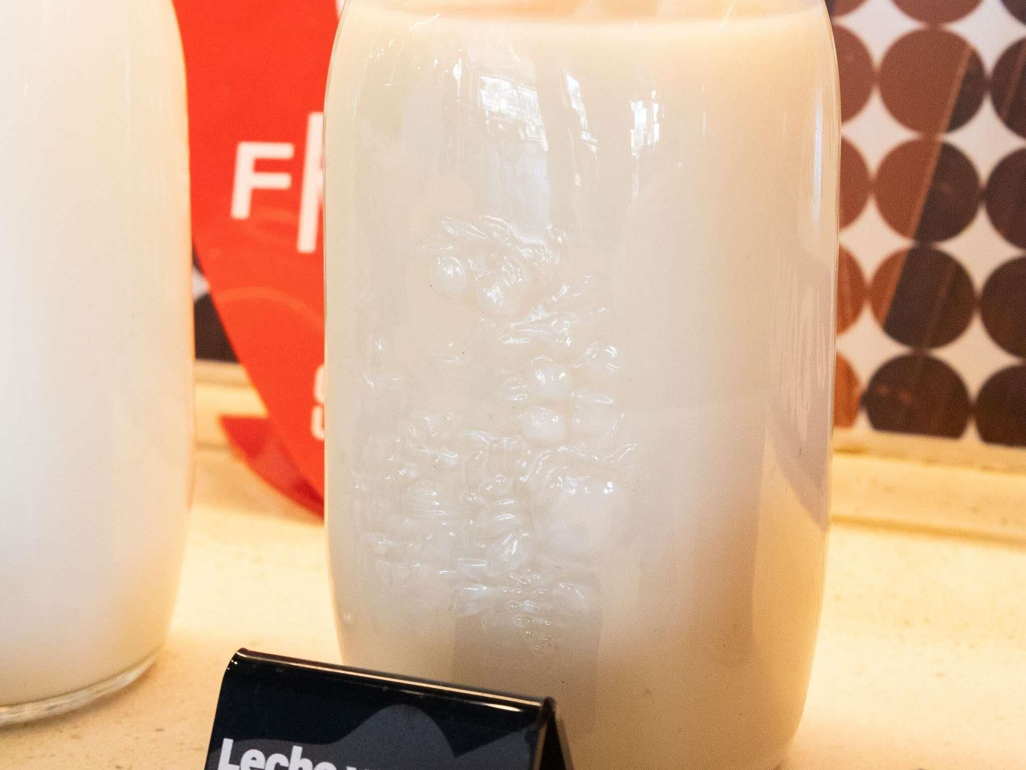 A clear glass container with a white substance, possibly a beverage, on a countertop.