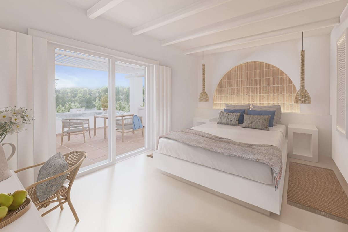 A bedroom with a large bed, a sitting area with a chair and table, and a view through a glass door to an outdoor patio.
