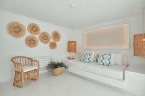 A modern living room with a white sofa, a wicker chair, and decorative wall art.