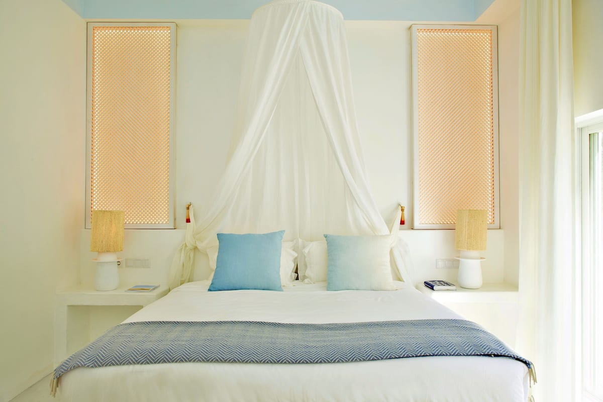 A bed with a canopy, bedside lamps, and pillows.