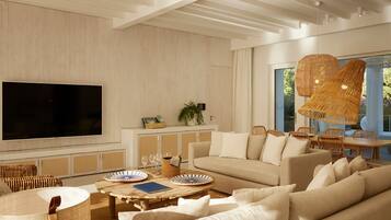 Una sala moderna con un televisor de pantalla plana grande, muebles de mimbre, un sofá y una zona de comedor con una mesa y sillas.