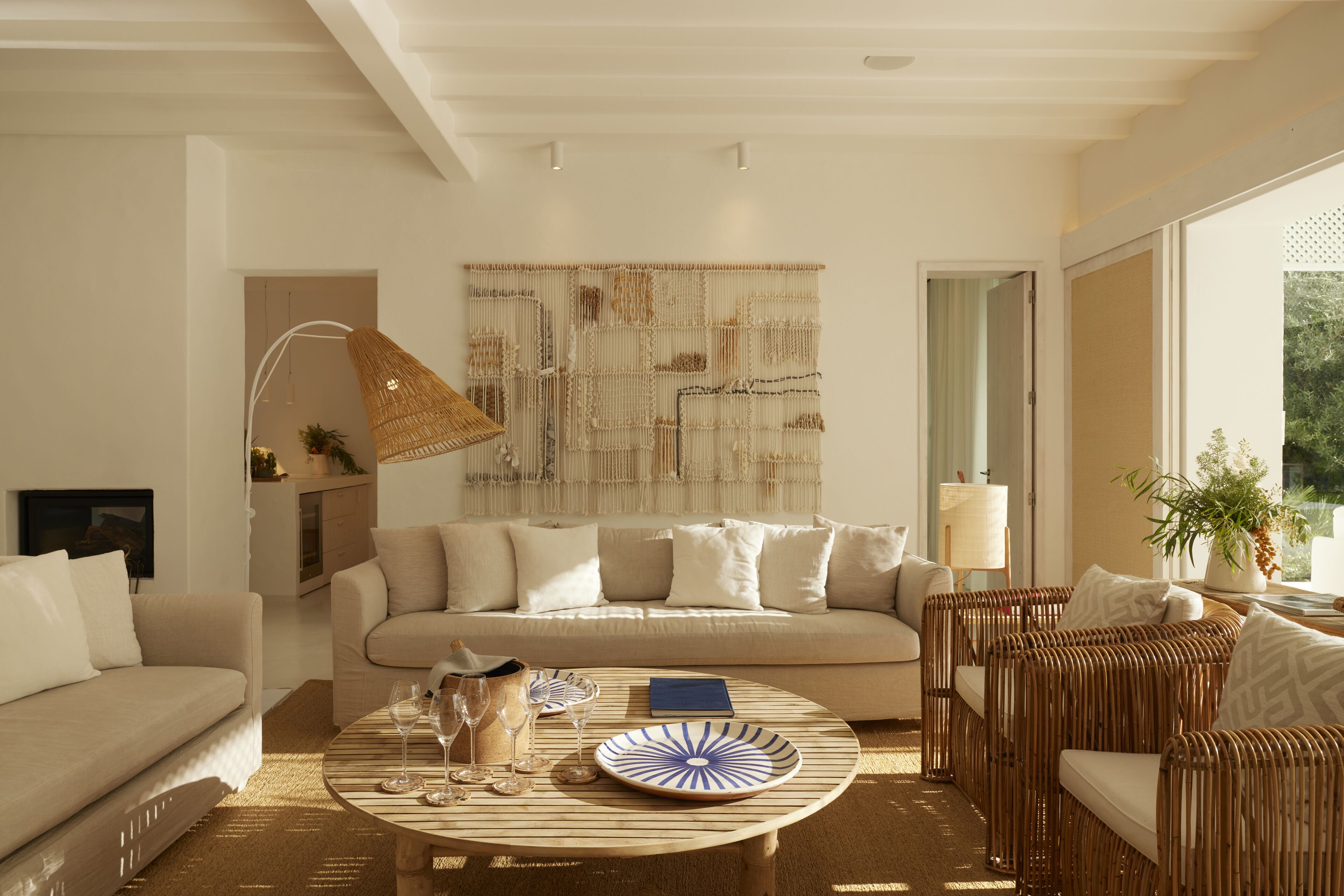 A modern living room with a sofa, a coffee table with glasses, a lamp, and a wall art piece.