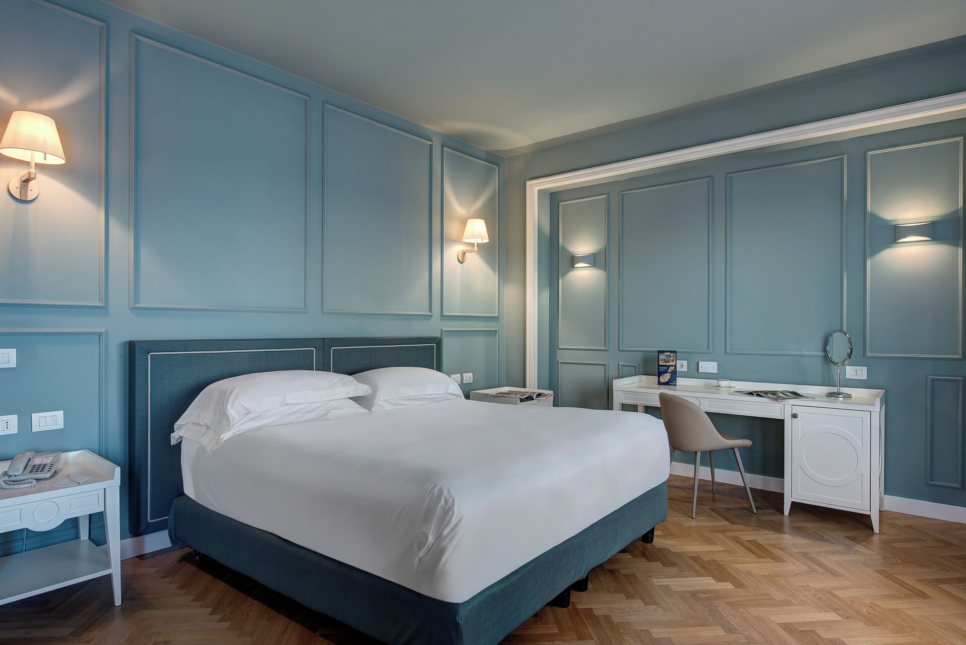 Siististi järjestetty hotellihuone, jossa on suuri sänky, työpöytä ja tuoli.