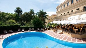 A swimming pool surrounded by lounge chairs and umbrellas, with a building in the background. - Imperial Hotel Tramontano (Sorrento)