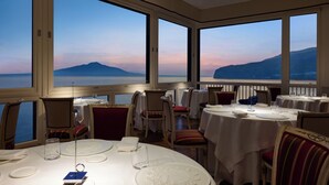 A restaurant with tables set for dining, large windows offering a view of the sea and mountains. - Imperial Hotel Tramontano (Sorrento)