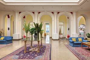 A spacious lobby with a high ceiling, arched columns, and a central area with a glass table surrounded by potted plants. - Imperial Hotel Tramontano (Sorrento)