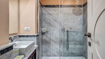 Ein modernes Badezimmer mit einer gläsernen Dusche, einem weißen Waschbecken und Marmorböden.