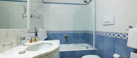 A bathroom with a marble sink, a bathtub, a toilet, and blue-tiled walls.
