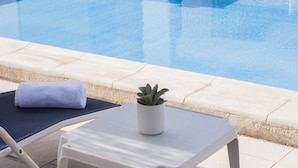 A poolside area with a lounge chair, a towel, and a potted plant. - Alexandra Hotel (St. Julian's)