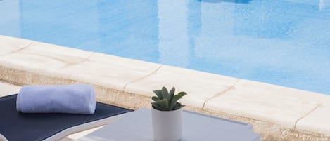 Ett område vid poolen med en solstol, en handduk och en krukväxt.