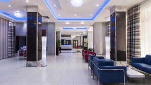 A modern lobby with marble columns, blue seating, and a reception desk. - Alexandra Hotel (St. Julian's)