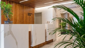 Una recepción con mostrador de madera, superficie de mármol y una planta en maceta.