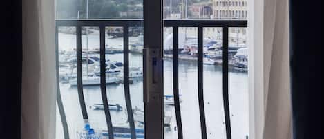 A balcony with a view of a marina, boats, and a distant building.