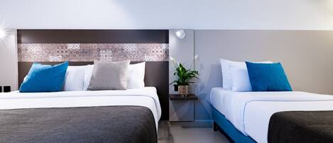 Une chambre d’hôtel moderne avec deux lits, une table de chevet et un panneau décoratif mural.