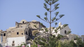 A building with a dome and a bell tower, surrounded by vegetation. - Paradise Resort (Santorini)