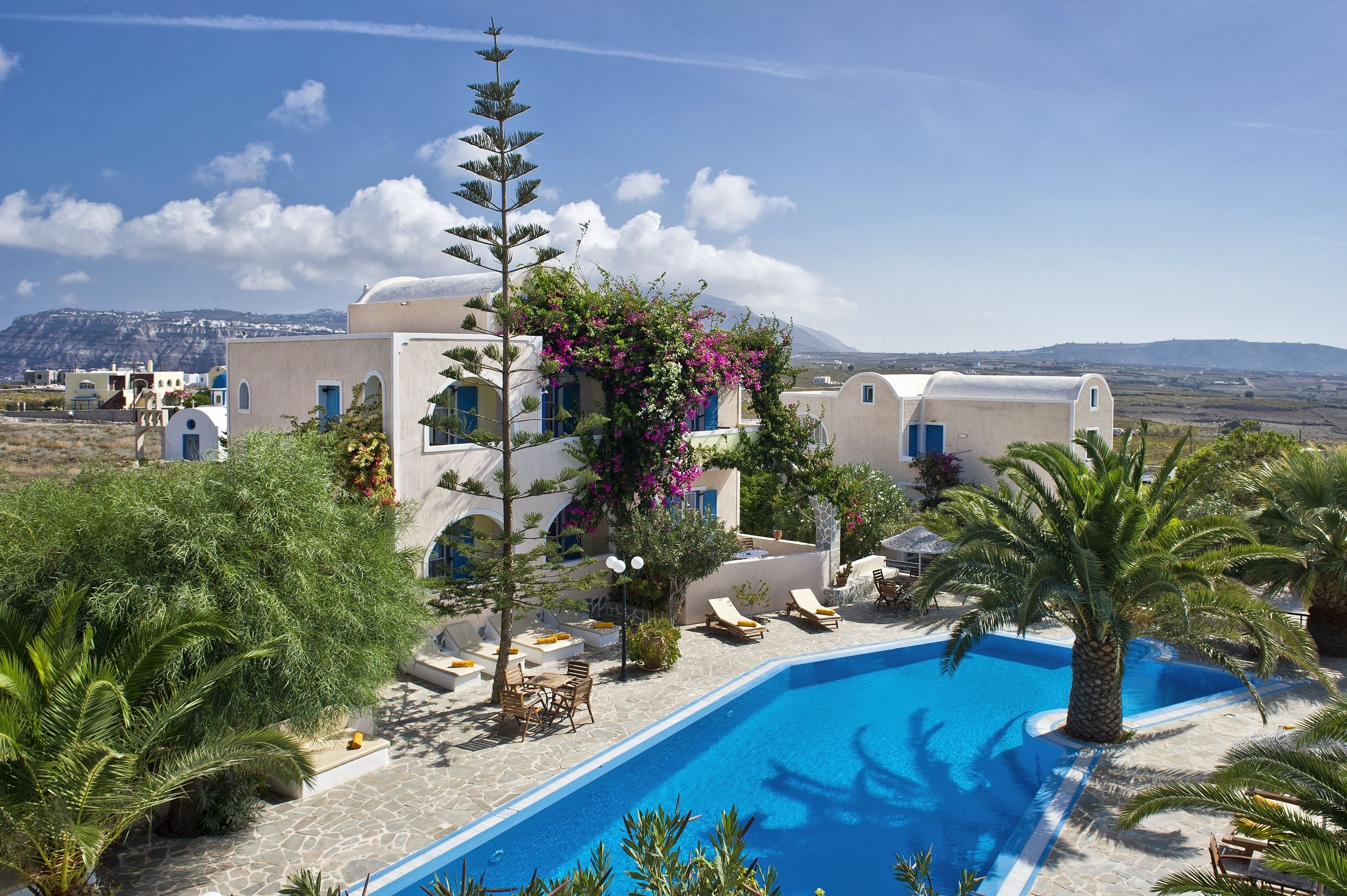 A resort with a swimming pool, lounge chairs, and a view of the landscape.