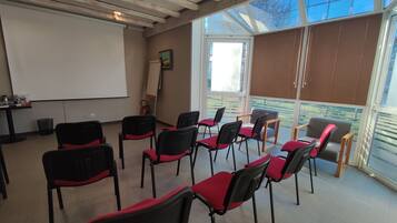 Una sala de conferencias con una pizarra, proyector y varias sillas dispuestas para una reunión.