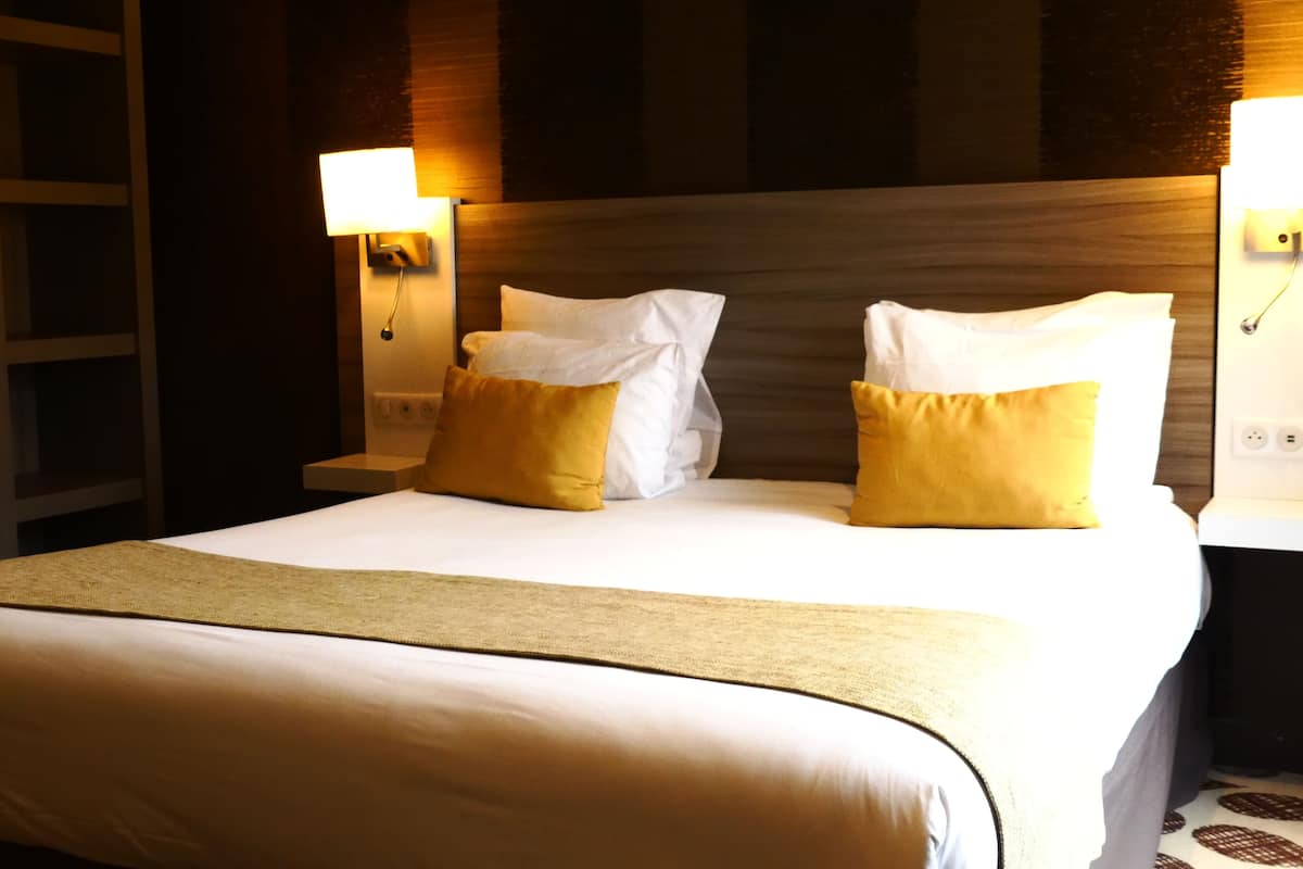 Une chambre d’hôtel avec un grand lit, deux lampes de chevet et une tête de lit en bois.