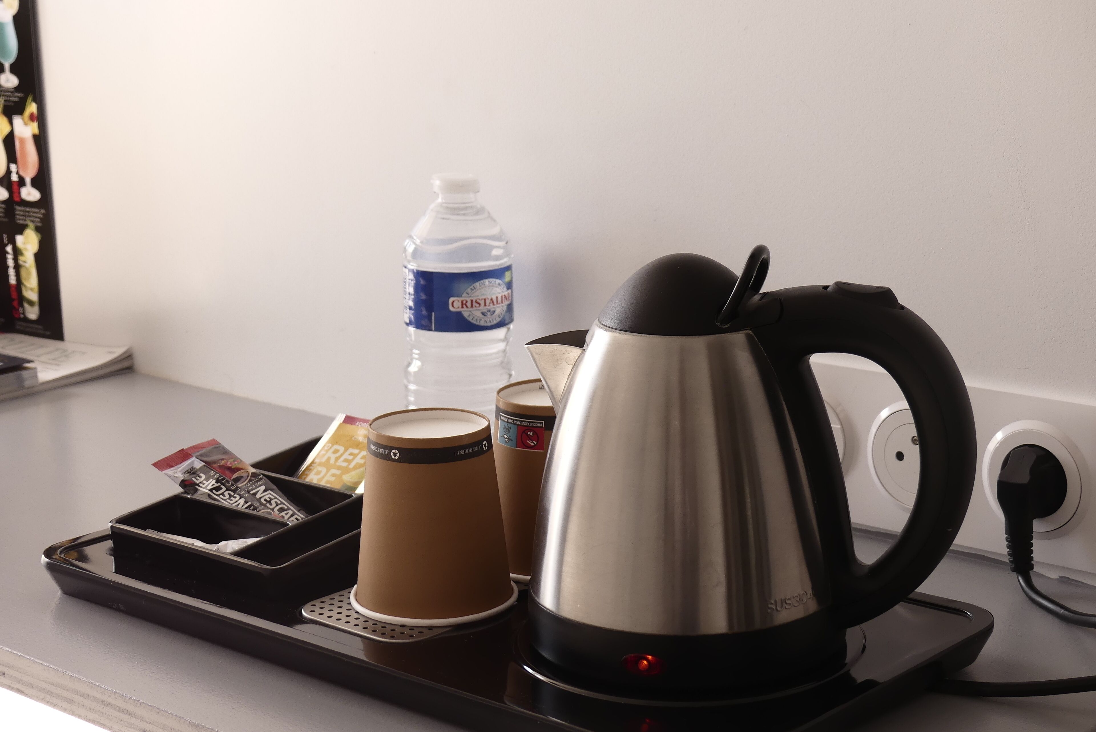 A coffee maker, a water bottle, and a tray with a packet of coffee creamer on a countertop.
