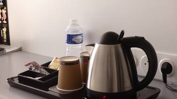 A coffee maker, a water bottle, and a tray with a packet of coffee creamer on a countertop.