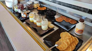 A buffet with various food items, including jars of preserves, bowls of fruits, and plates of pancakes. - Le Provençal (Bordeaux)