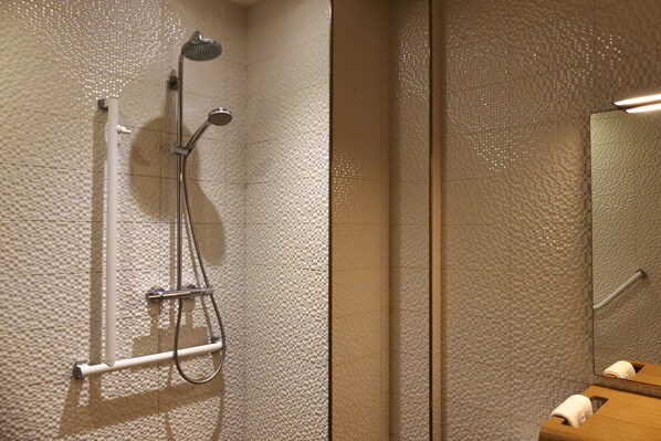 Une salle de bain moderne équipée d’une douche, d’un sèche-mains et d’un meuble-lavabo en bois avec un miroir.