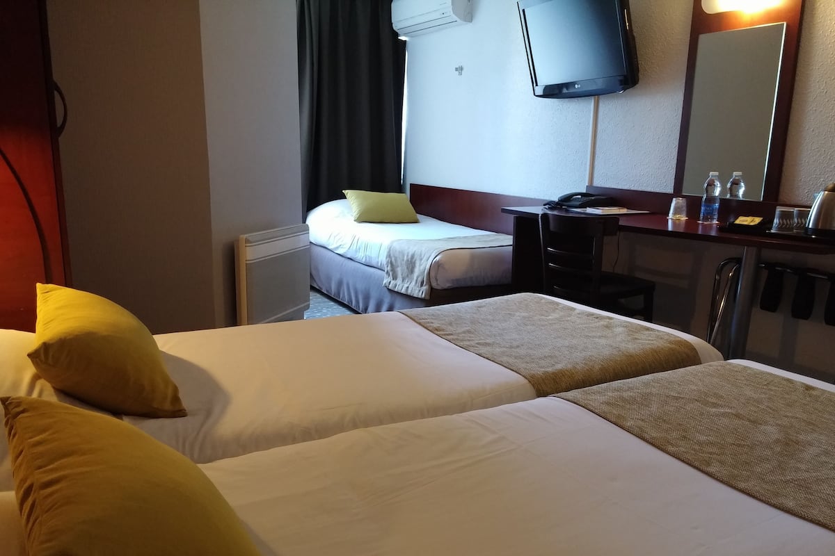 Une chambre d’hôtel avec deux lits, un bureau, une chaise, une télévision et un miroir.